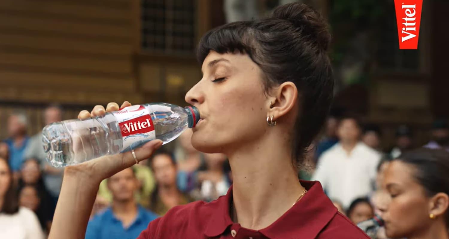 Femme tenant une bouteille Vittel.