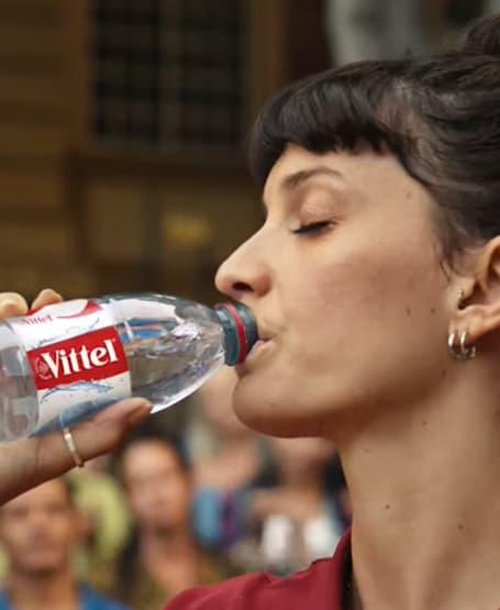 Femme tenant une bouteille Vittel.